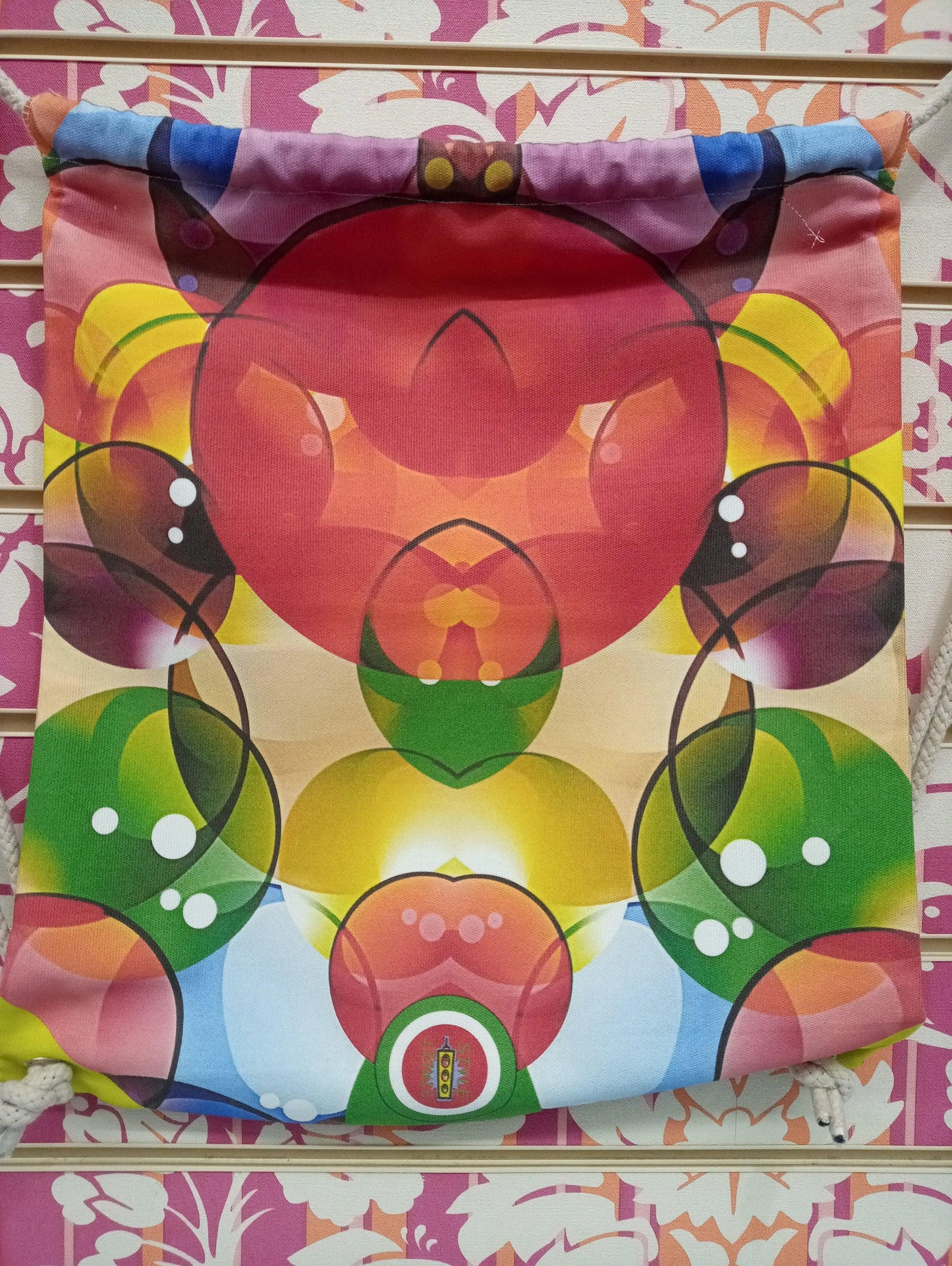 Zaino a sacca streetwear con stampa colorata astratta, esposto su sfondo floreale, Street Style Rimini