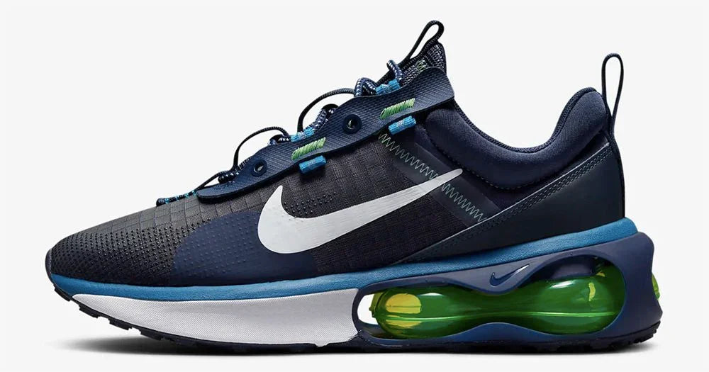 Sneaker uomo stile streetwear, colore blu navy con dettagli verdi, tessuto tecnico e suola trasparente con cuscinetto d’aria, design urban moderno