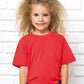 Bambina streetwear con t-shirt rossa, fiocco rosso e sfondo muro bianco, stile urban