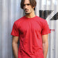 Uomo in t-shirt rossa streetwear davanti a muro industriale, stile urban casual
