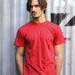 Uomo street style con t-shirt rossa e pantaloni beige davanti a parete industriale grigia