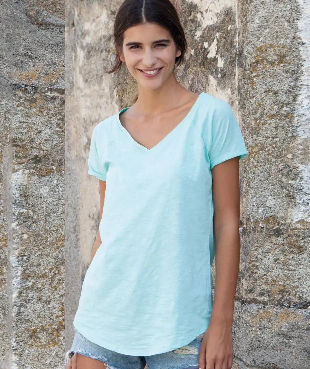 Donna con t-shirt azzurra e shorts jeans streetwear, sfondo muro in pietra, street style