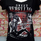 T-shirt donna streetwear nera con stampa Sweet Rebellion e grafica urban rock, esposta in negozio.