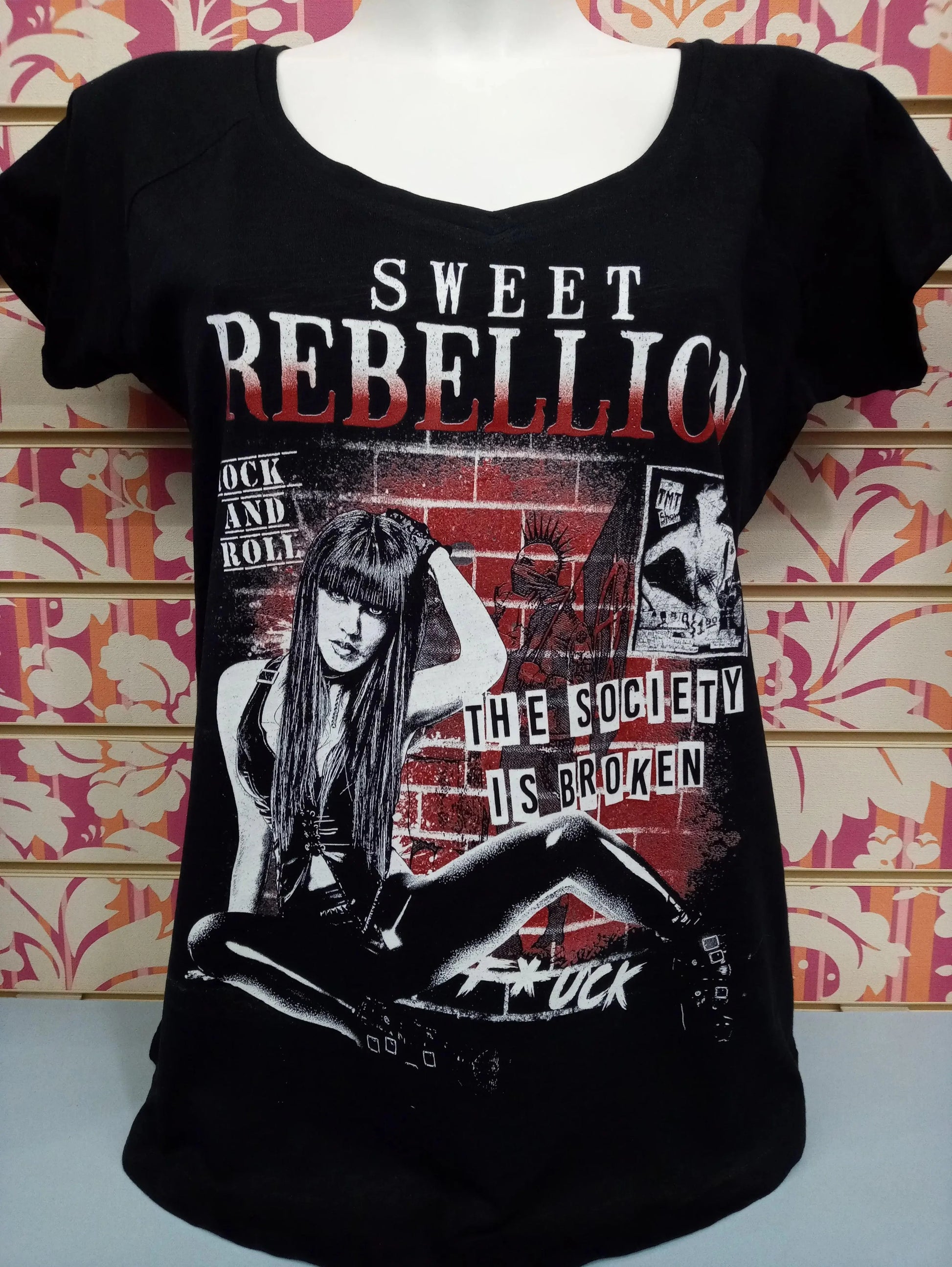 T-shirt donna streetwear nera con stampa Sweet Rebellion e grafica urban rock, esposta in negozio.