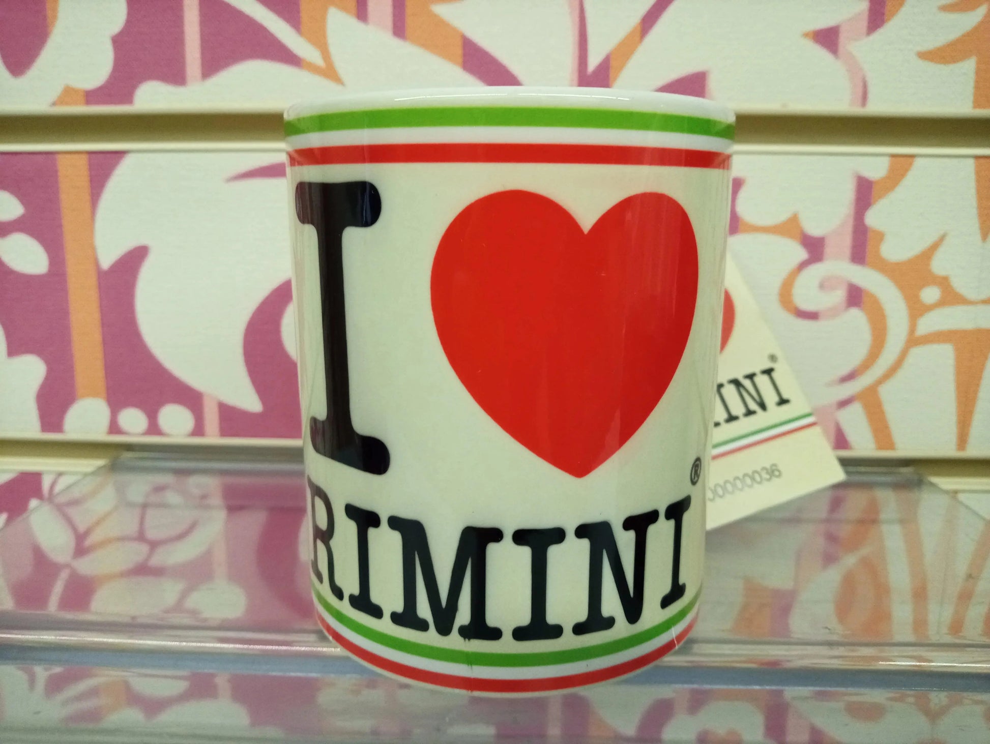 Tazza mug bianca con scritta I love Rimini, stile streetwear, su sfondo decorato colorato.