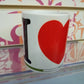 Tazza mug bianca con scritta I Love Rimini, stile streetwear, su sfondo colorato.