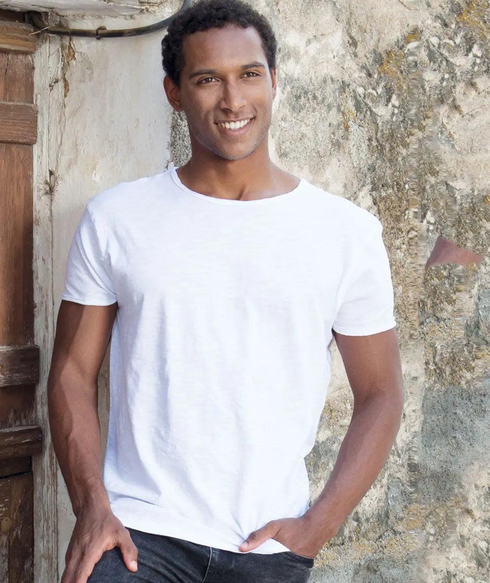 Uomo indossa t-shirt bianca cotone streetwear, stile urban, davanti a muro rustico.