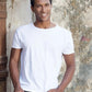 Uomo con t-shirt bianca cotone, street style urban, sfondo muro rustico, moda Rimini.