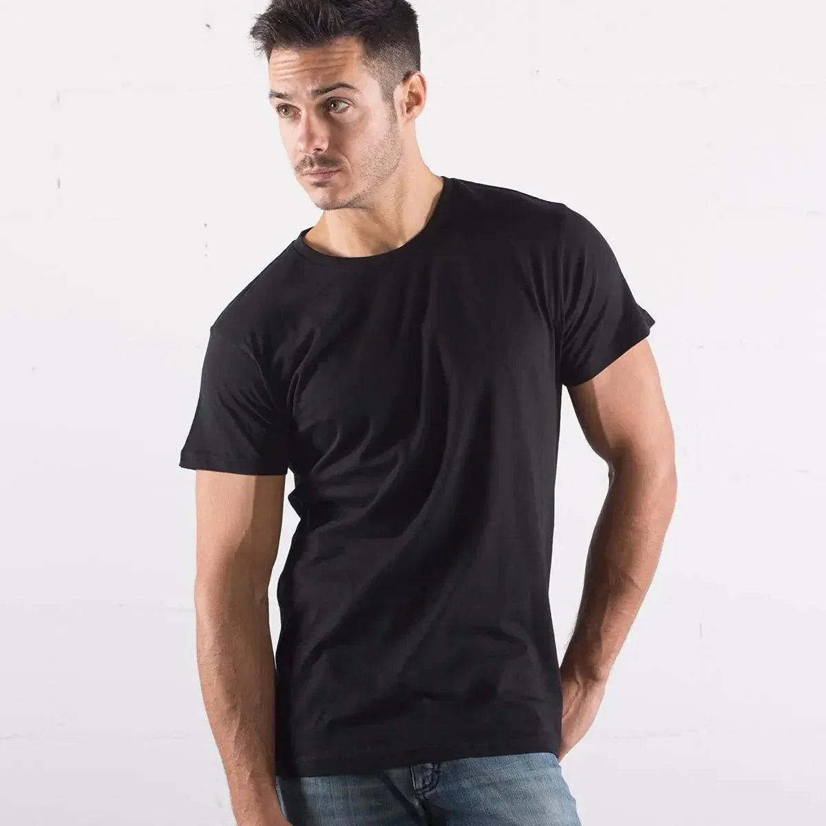 Uomo con t-shirt nera basic streetwear e jeans, stile street style moderno su sfondo chiaro