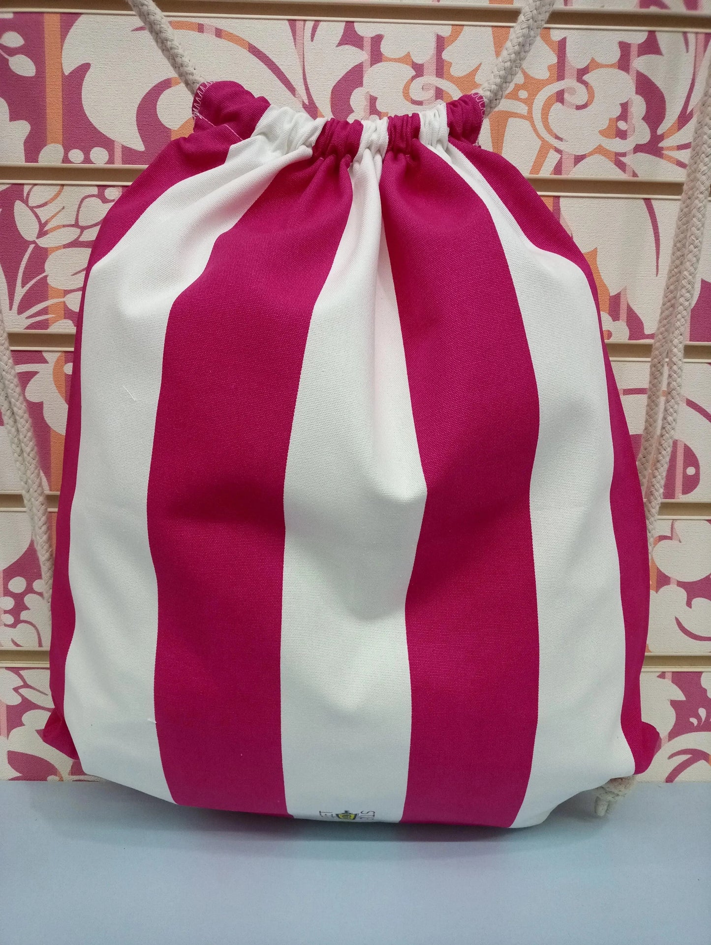 Zaino a sacca streetwear con righe fucsia e bianche, stile urban su sfondo decorato