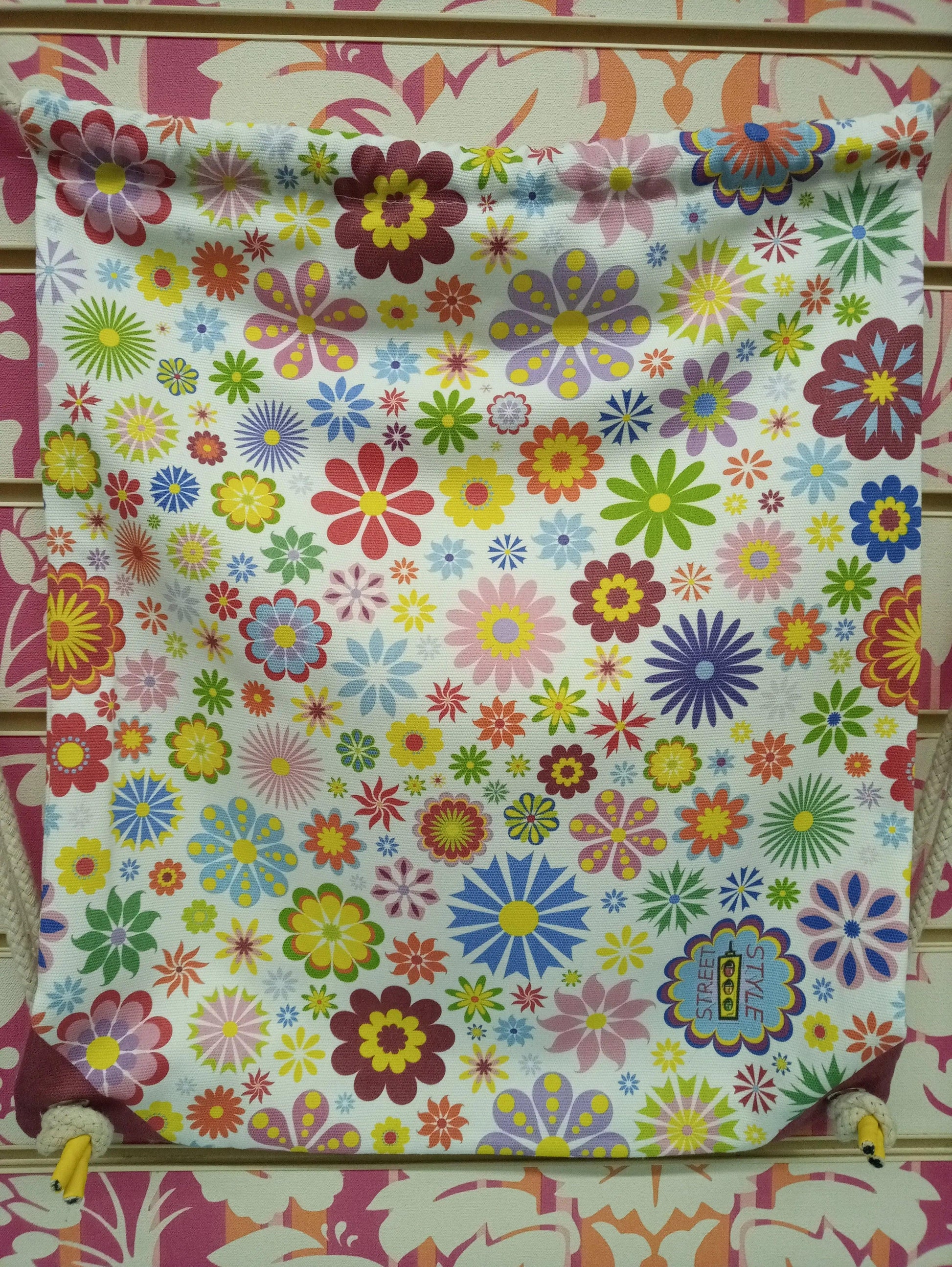 Zaino a sacca multicolor floreale Street Style, esposto su sfondo decorato, moda streetwear.