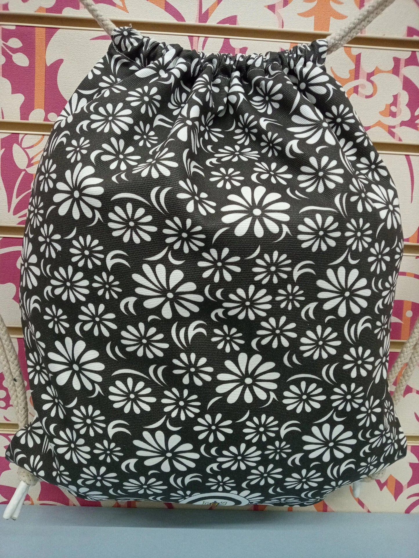 Zaino a sacca nero con motivo floreale bianco, street style, essenziale urban fashion.