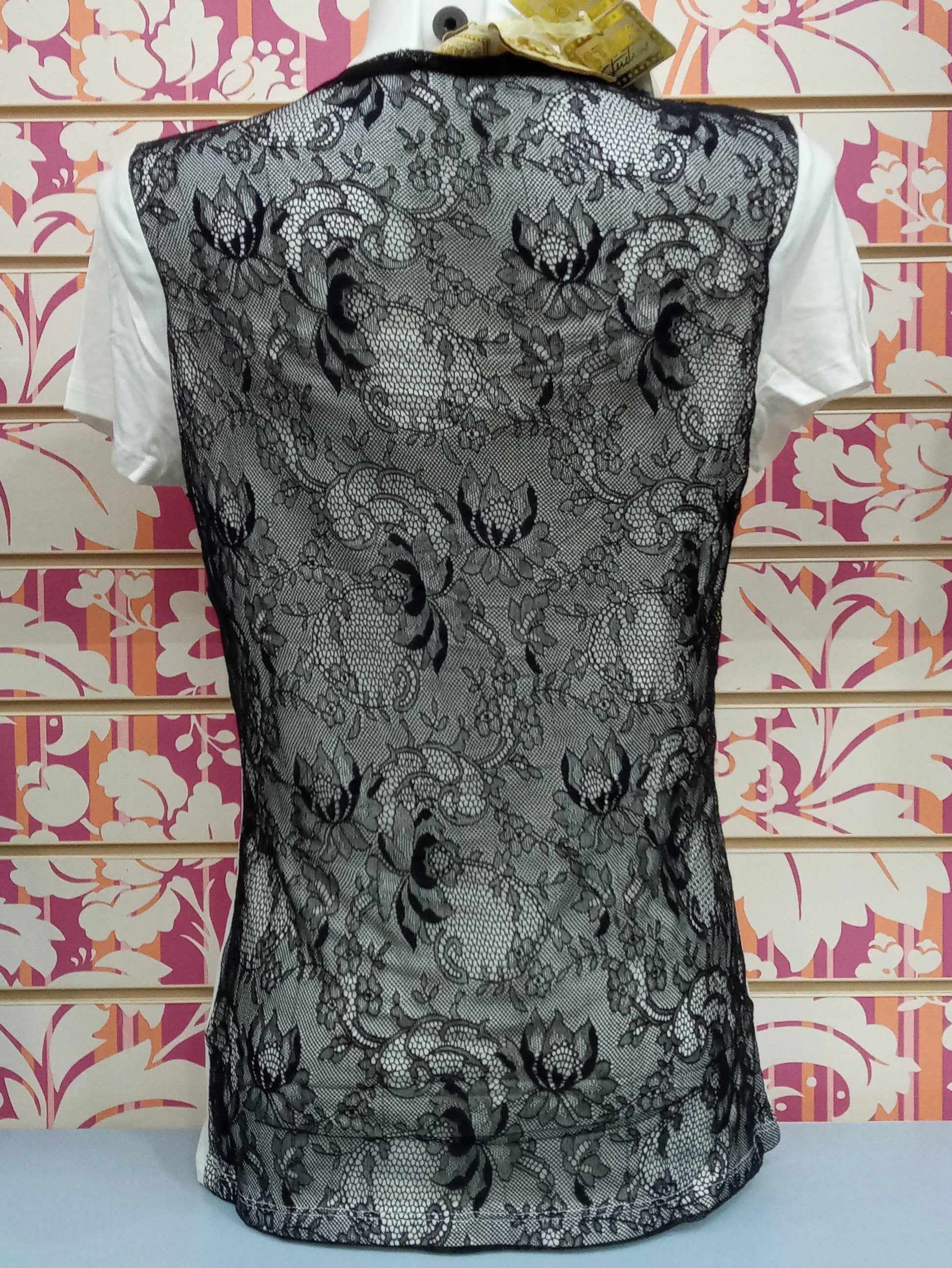 T-shirt donna street style bianca con retro in pizzo nero floreale, sfondo colorato.